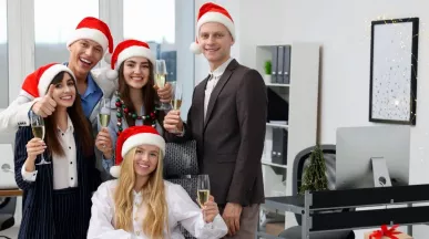 Equipo de oficina celebrando la Navidad con gorros rojos y copas de brindis