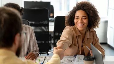 Persona joven sonriendo y estrechando la mano en una entrevista laboral, representando el crecimiento del mercado laboral uruguayo.