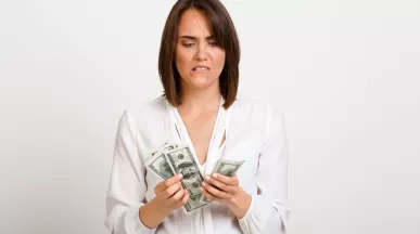Mujer observando billetes de dinero con gesto de preocupación, reflejando la brecha entre salario real y salario percibido.