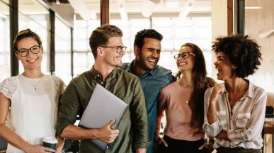 Equipo de trabajo sonriendo en la oficina, reflejando motivación y buen clima laboral en un entorno corporativo en Uruguay.