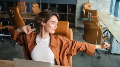 Colaboradora relajada disfrutando de sus beneficios laborales flexibles, en un entorno de trabajo moderno, enfocado en flexibilidad y bienestar