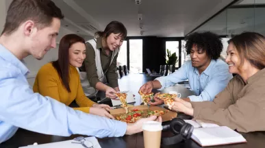 Equipo de trabajo compartiendo una comida en oficina, relacionado con gestión de gastos y reducción de costos de alimentación en una empresa