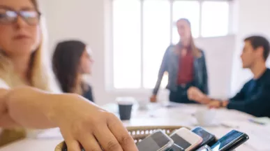 Personas dejando sus celulares en una mesa durante una reunión de trabajo para promover el bienestar digital y reducir el uso excesivo del celular.