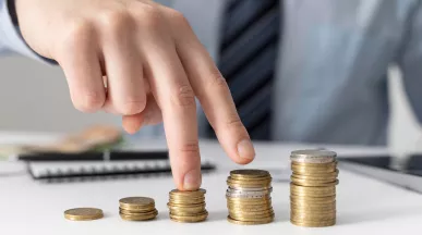 Mano acomodando pilas de monedas que representan el crecimiento de los salarios en Uruguay y la evolución del poder adquisitivo de los trabajadores.
