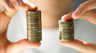Manos sostienen dos pilas de monedas de diferente altura para representar un aumento de sueldo.