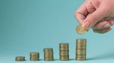 Mano colocando una moneda sobre pilas crecientes que representan el ajuste salarial 2026 en Uruguay.