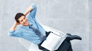 Hombre sonriente con una computadora portátil, en representación de los beneficios de la semana laboral de 4 días.