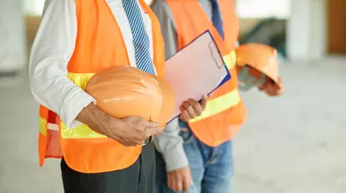 Profesionales con chalecos de seguridad sostienen cascos y una carpeta, representando la salud ocupacional en el trabajo.