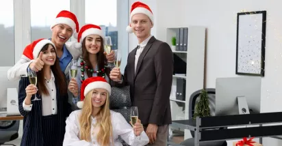 Equipo de oficina celebrando la Navidad con gorros rojos y copas de brindis