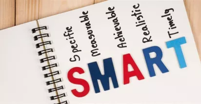 Cuaderno con la palabra SMART y sus componentes específicos, medibles, alcanzables, relevantes y con plazo, representando la metodología para definir objetivos SMART.