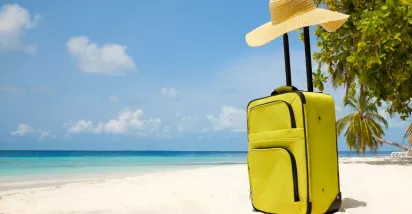 Valija sobre la arena frente al mar, representando el descanso y las vacaciones laborales.