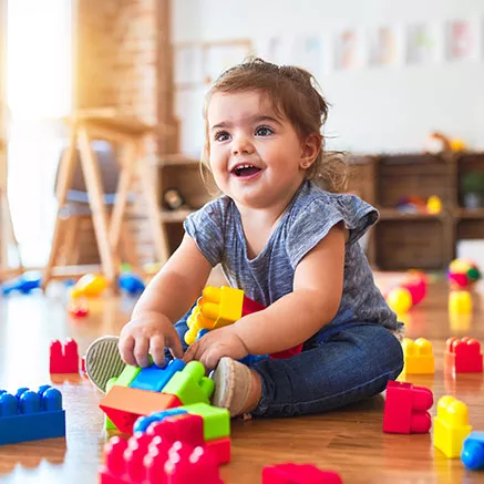Niño pequeño jugando con juguetes en el suelo